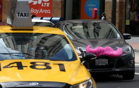 A Lyft Inc. car drives behind a taxi in San Francisco, California.