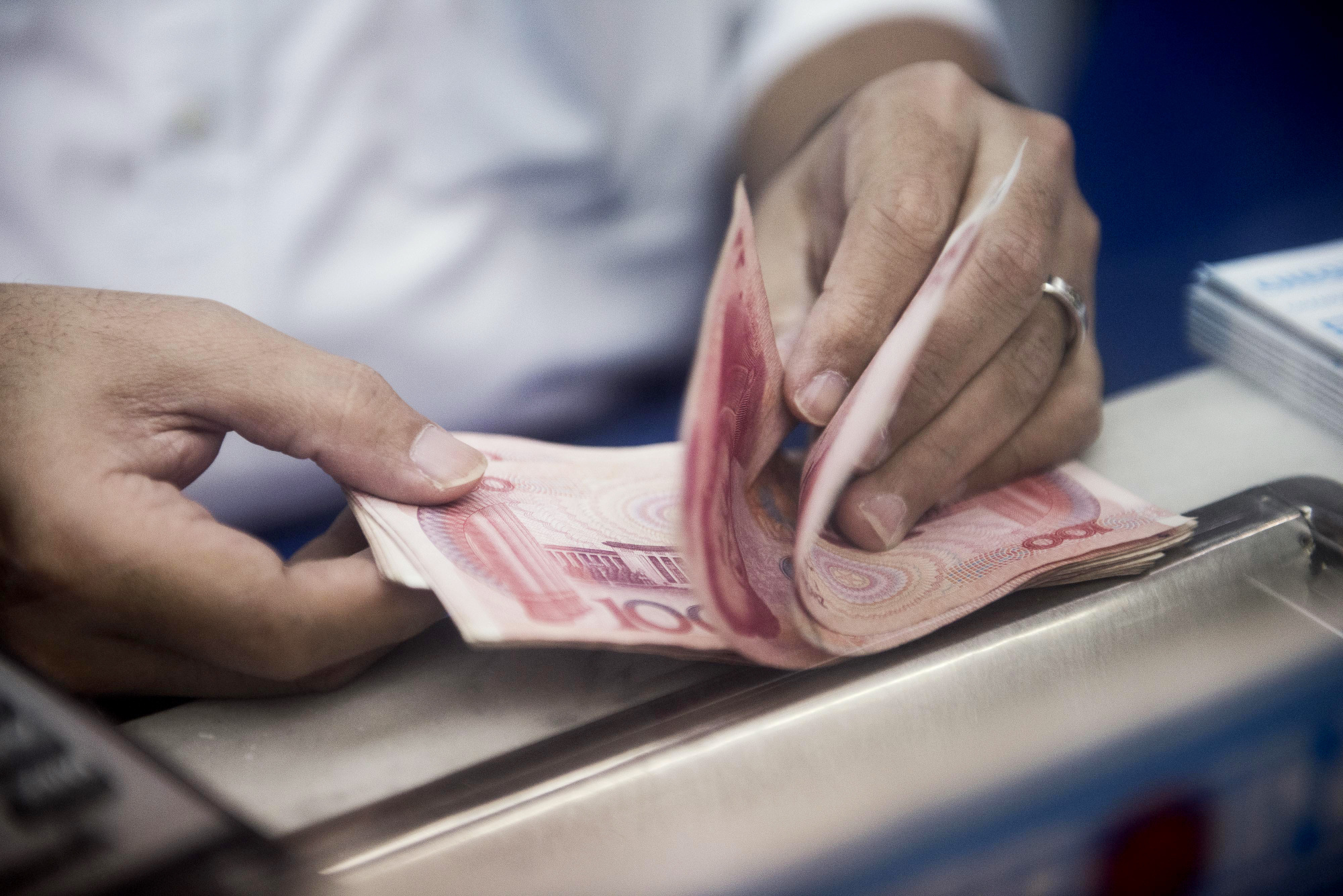 A person counts Chinese&nbsp;yuan banknotes in Hong Kong.&nbsp;
