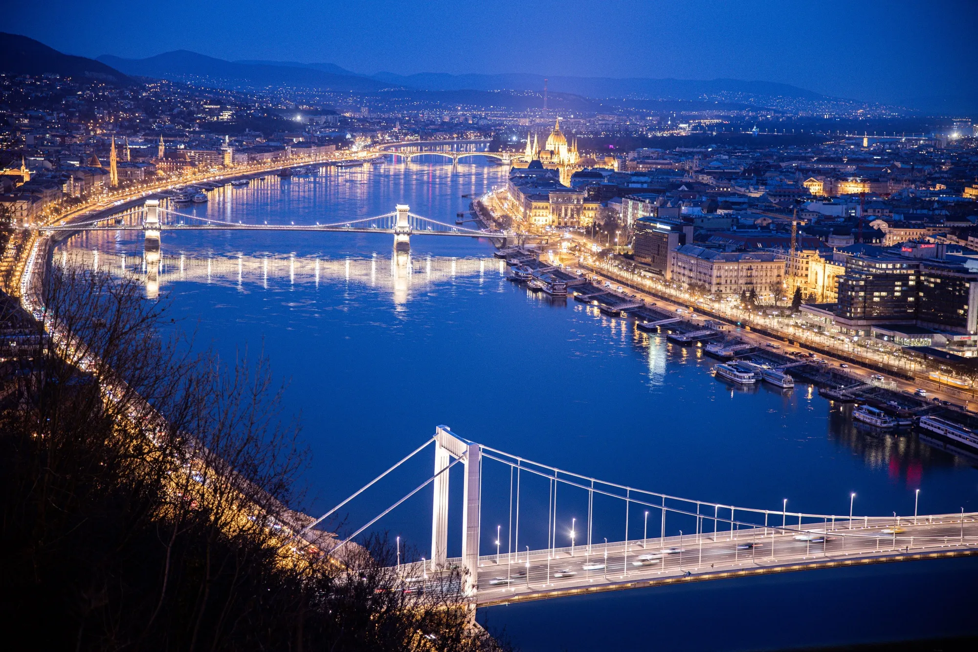 Lights illuminate the city skyline and the Chain Bridge at night in Budapest.