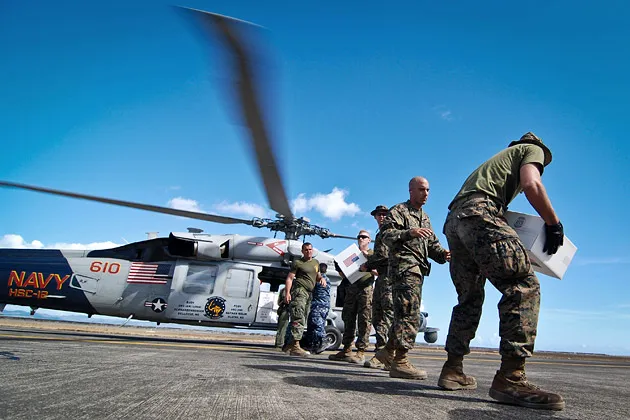 U.S. service members unload relief supplies from a Black Hawk helicopter at Tacloban airport in the Philippines