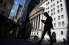 A pedestrian wearing a face mask looks at a smartphone while passing in front of the New York Stock Exchange (NYSE) in New York, U.S., on Monday, July 20, 2020. U.S. stocks fluctuated in light trading as investors are keeping an eye on Washington, where lawmakers will begin hammering out a rescue package to replace some of the expiring benefits earlier versions contained.