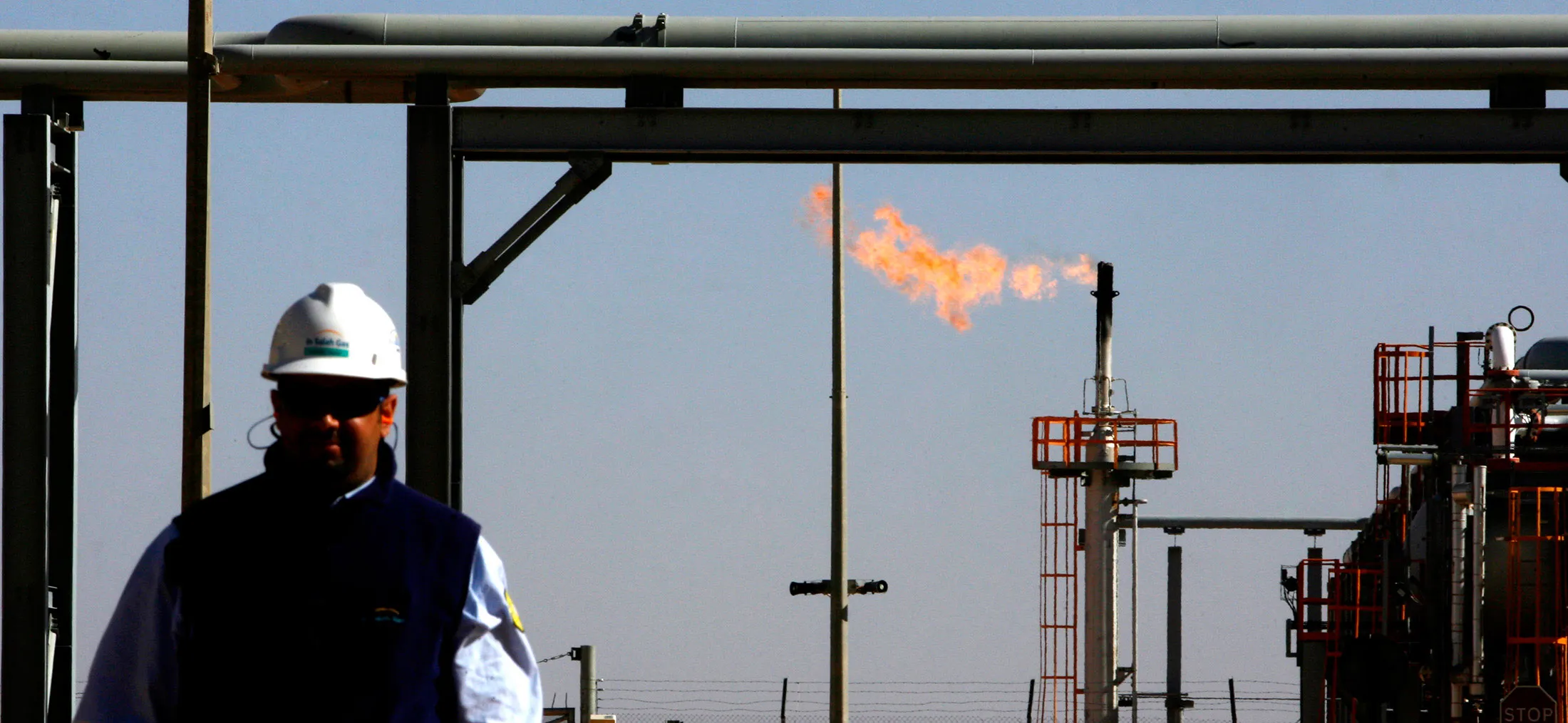 An employee walks in front of a gas flare at the In Salah Ga