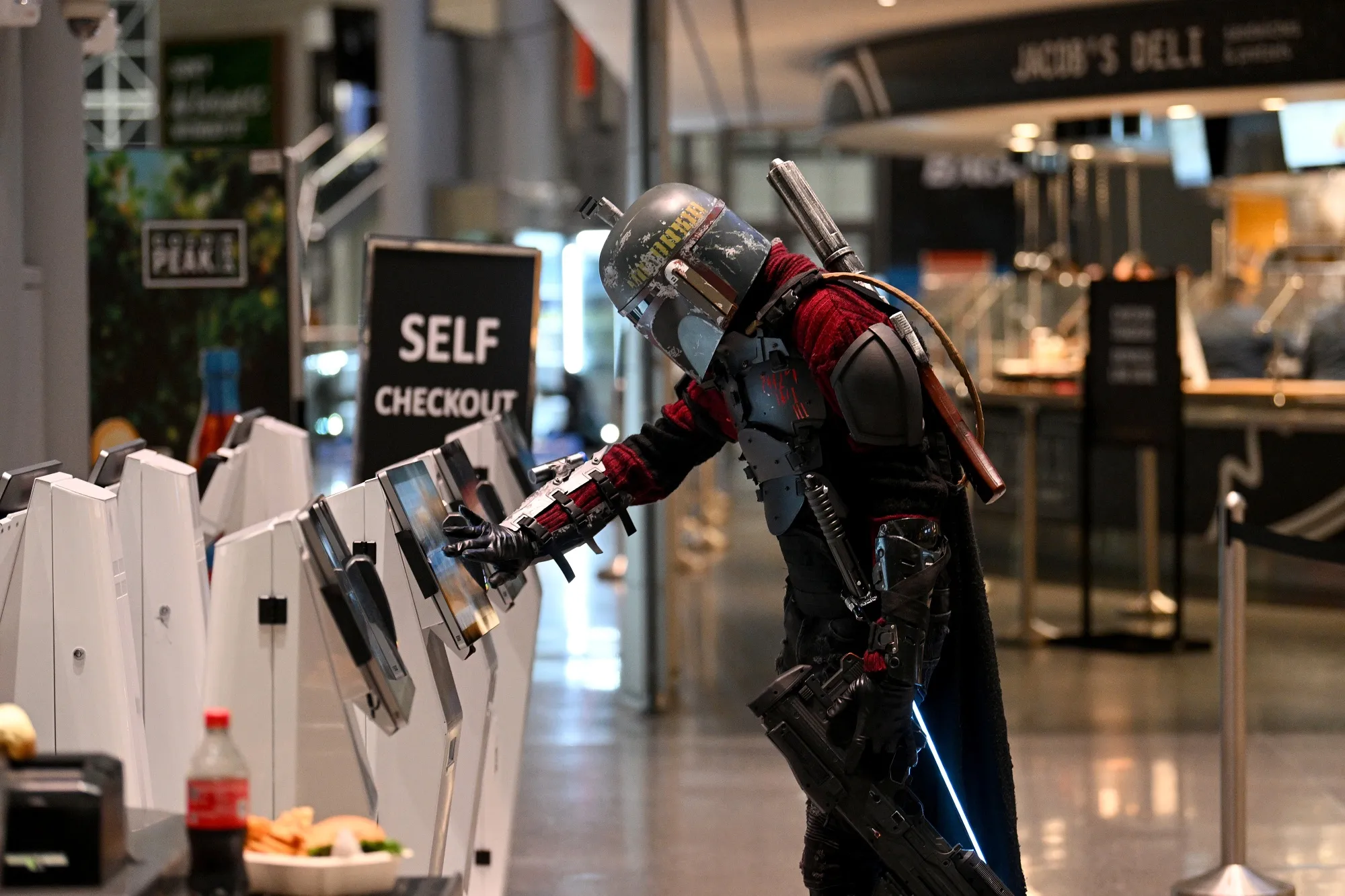 A cosplayer dressed as Boba Fett uses a self checkout machine during New York Comic Con 2022.&nbsp;
