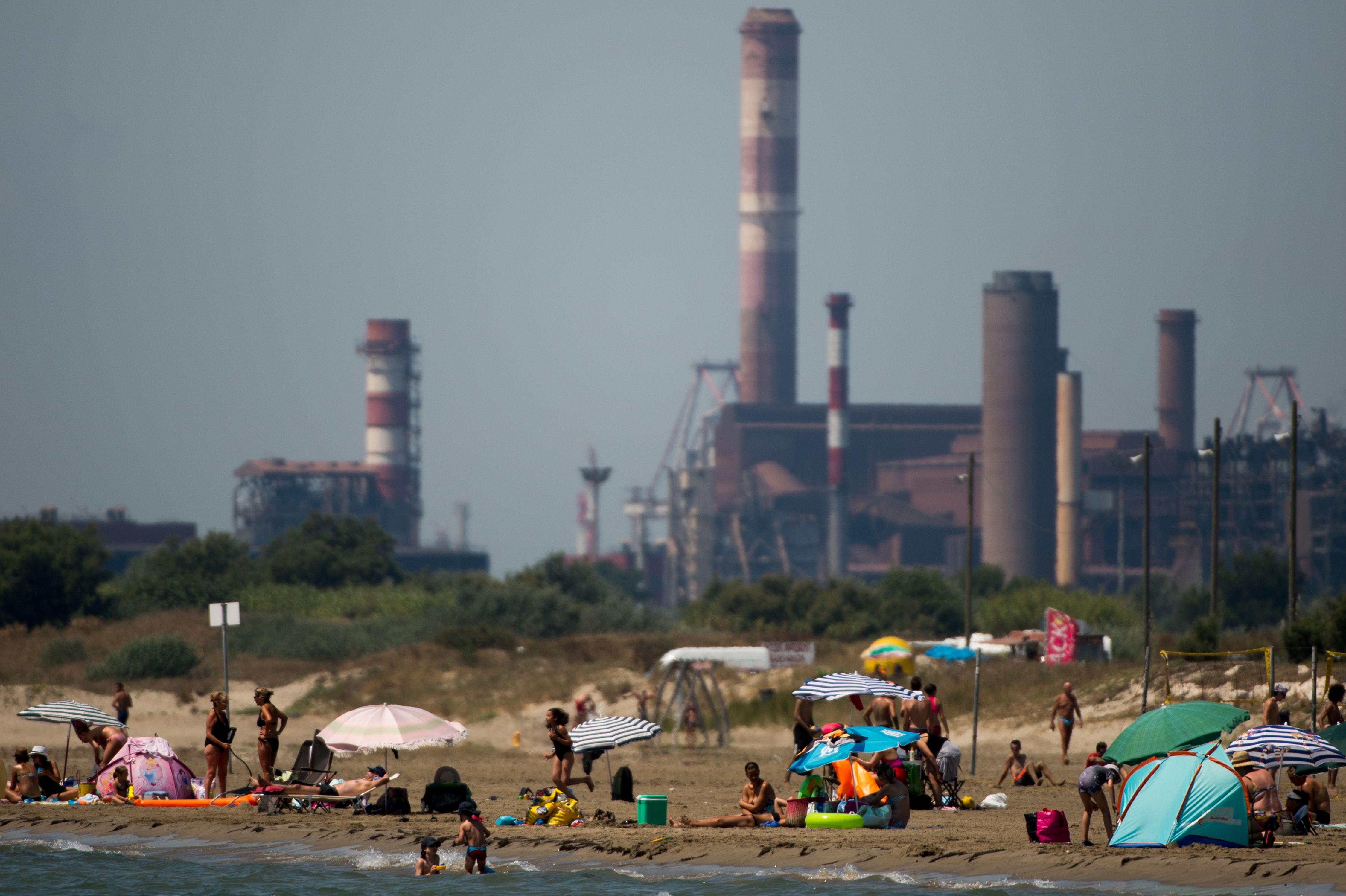 People bathe in the sea next to an industrial area in Fos-sur Mer, southern France.