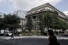 Pedestrians walk past the Bank of Japan (BOJ) headquarters in Tokyo, Japan, on Tuesday, July 31, 2018. The central bank left its key interest rates unchanged while announcing policy tweaks, including a shift in purchases of exchange-traded funds toward assets linked to the Topix equities index and flexibility in bond operations.