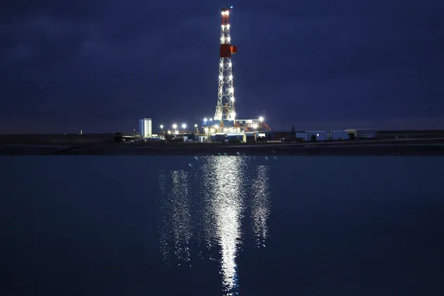 An oil rig reflected in a fracking pond on the Giddings Estate, a 10,000-acre field in Midland, Texas