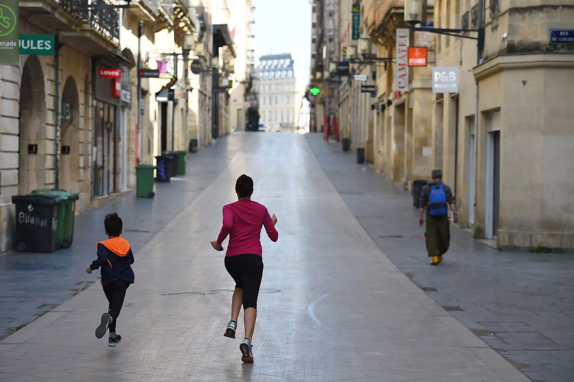 A woman and her son run in the deserted Sainte-Catherine street in Bordeaux, during Covid-19 restrictions.&nbsp;