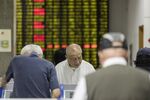Investors stand at trading terminals in front of an electronic stock board at a securities brokerage in Shanghai, China, on Wednesday, May 30, 2018.
