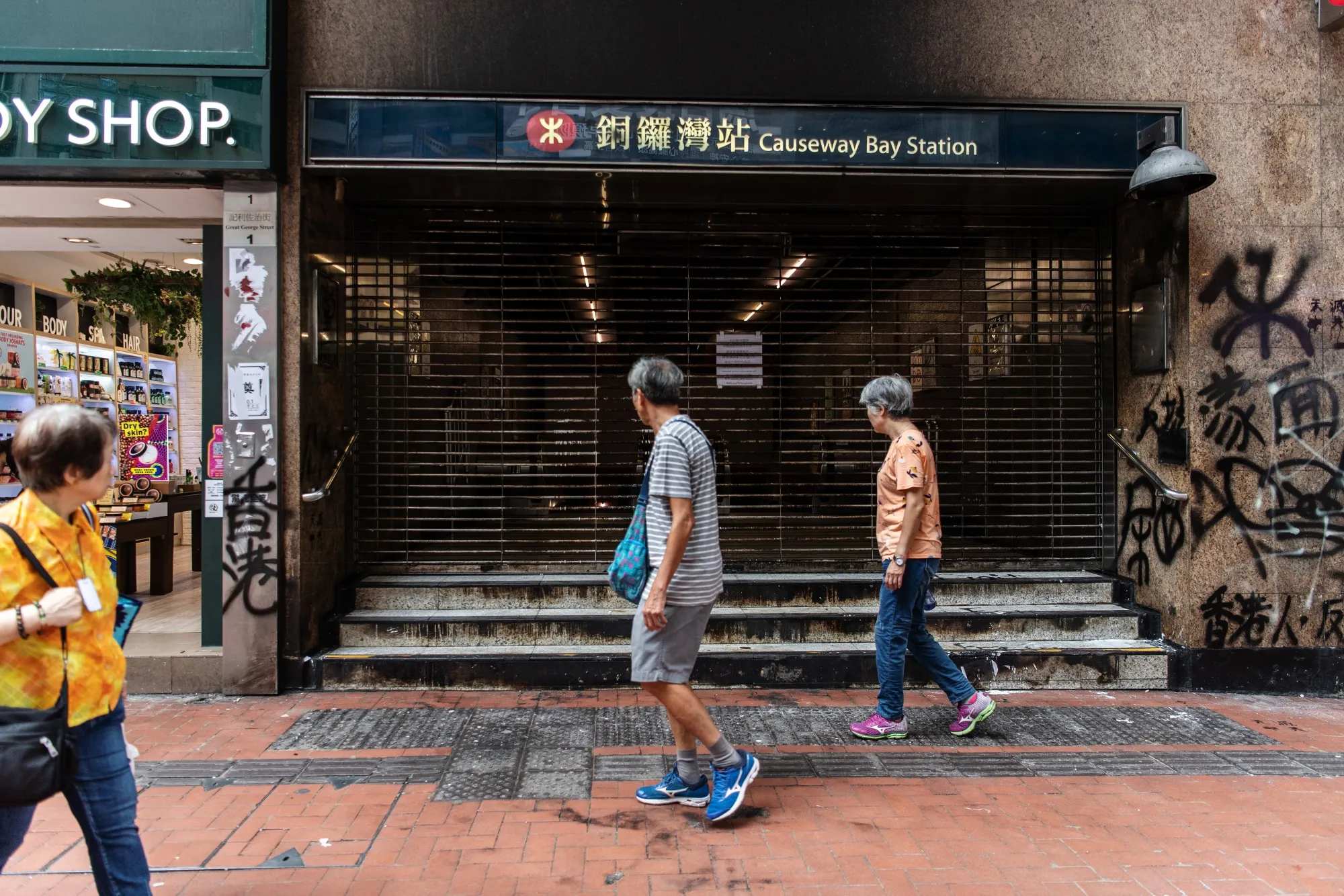 Pedestrians walk past the shuttered Causeway Bay Station in the Causeway Bay district of Hong Kong on Oct. 7.