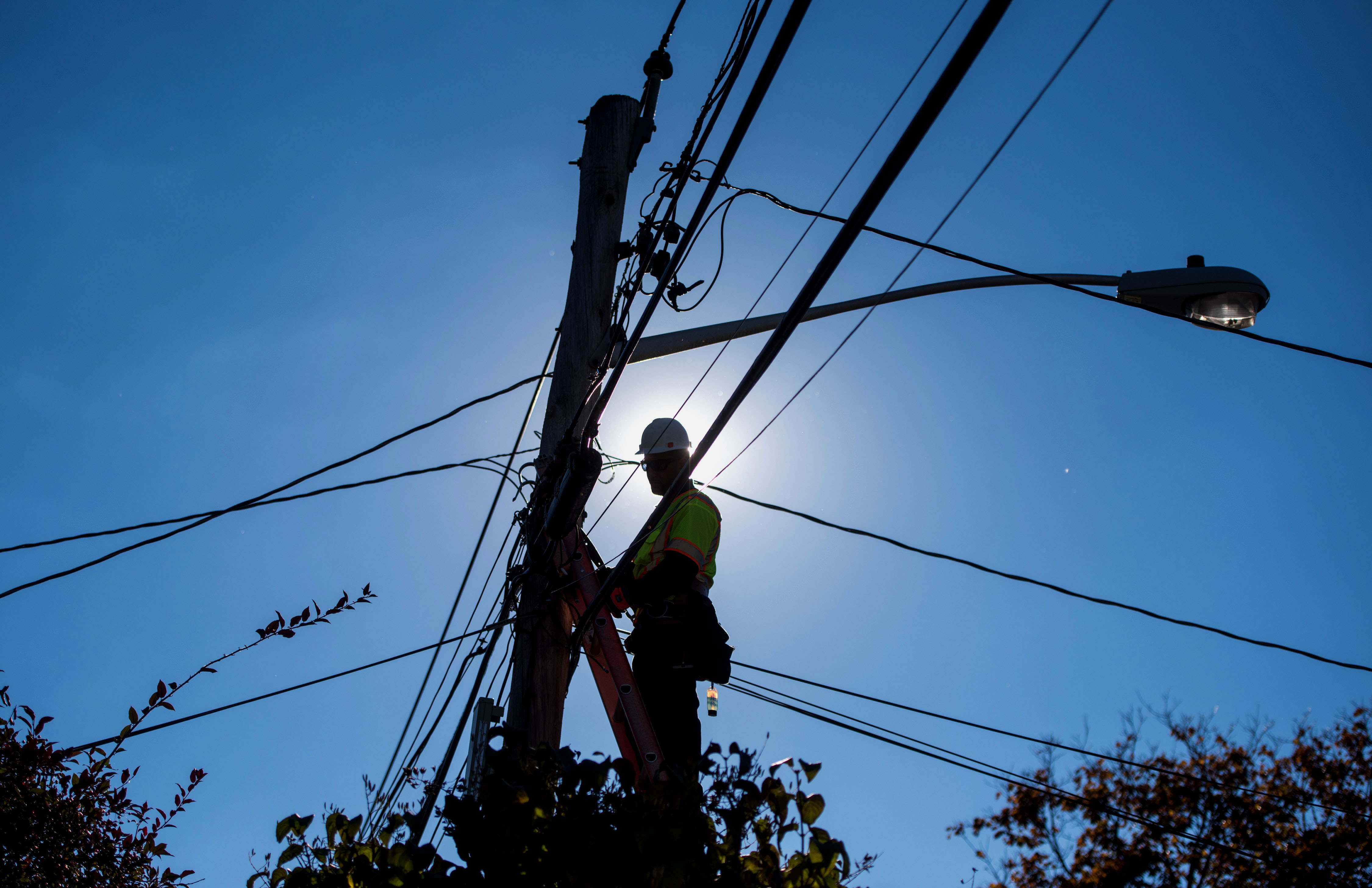 The silhouette of a&nbsp;technician is seen performing maintenance on&nbsp;network poles in Leonia, New Jersey.
