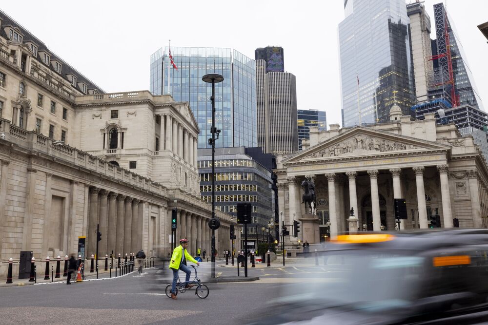 A cyclist rides a Brompton bicycle past the Bank of England, left, and Royal Exchange building, in the City financial district in London, U.K., on Thursday, Dec. 16, 2021. 