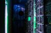 Lights illuminate ethernet cables on mining rigs inside a shipping container converted into a mobile cryptocurrency mining farm.