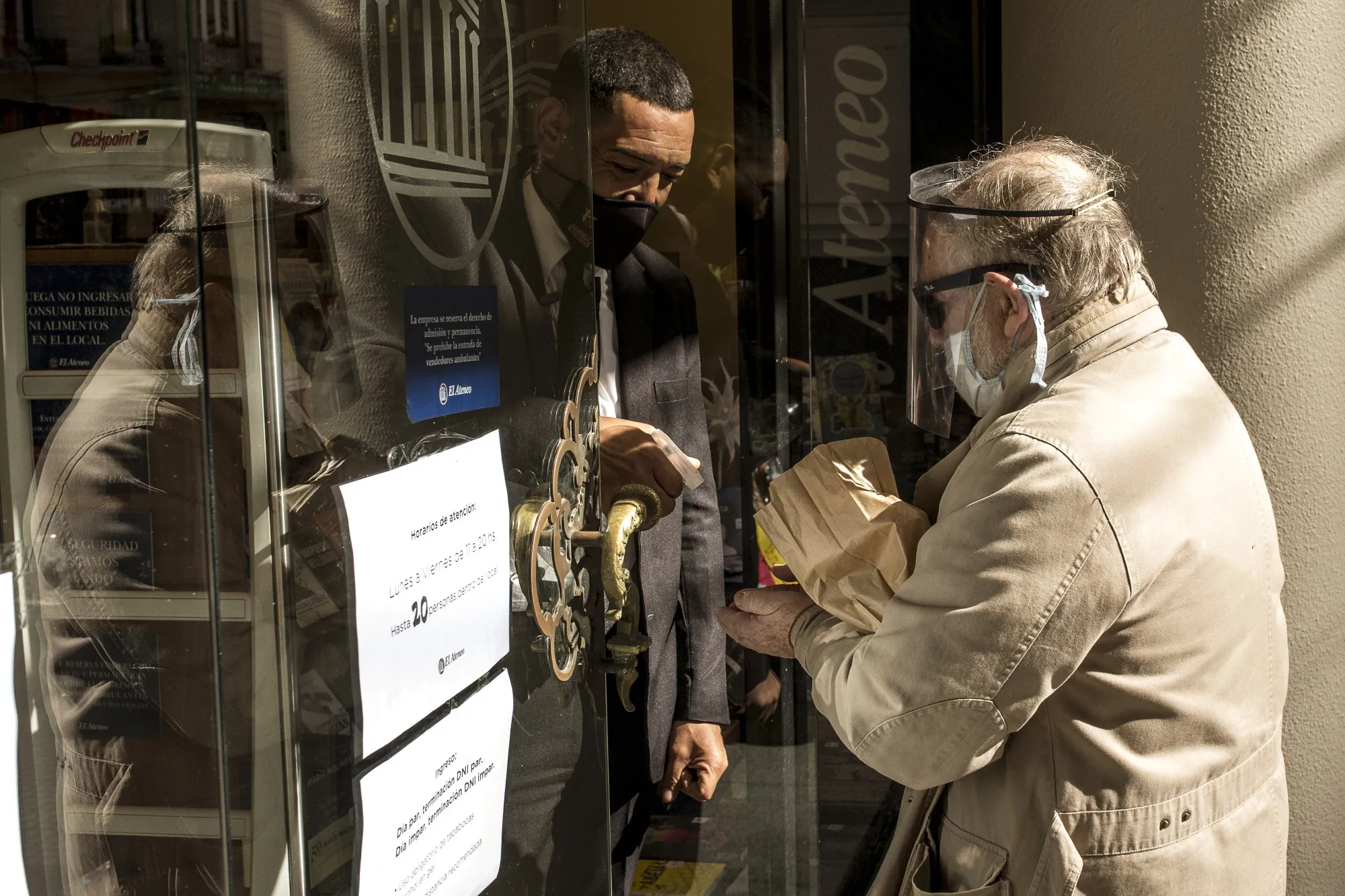 A customer wearing a protective mask and face shield uses hand sanitizer before entering a store in Buenos Aires, Argentina,&nbsp;May 14.