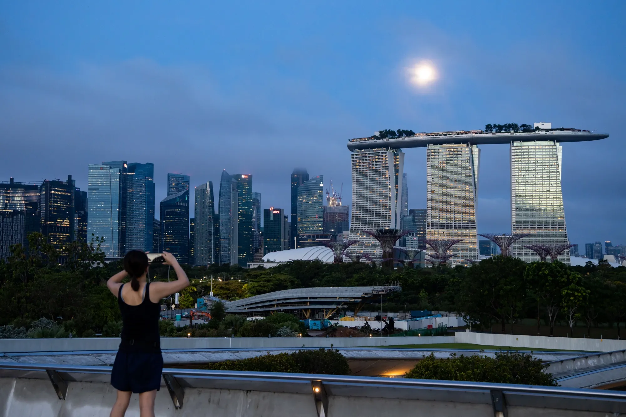 A person with a smartphone takes a photograph of the Marina Bay Sands hotel and casino.