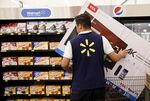 An employee moves a TCL Corp. television in shopping cart at a Wal-Mart Stores Inc. location in Burbank, California, U.S.