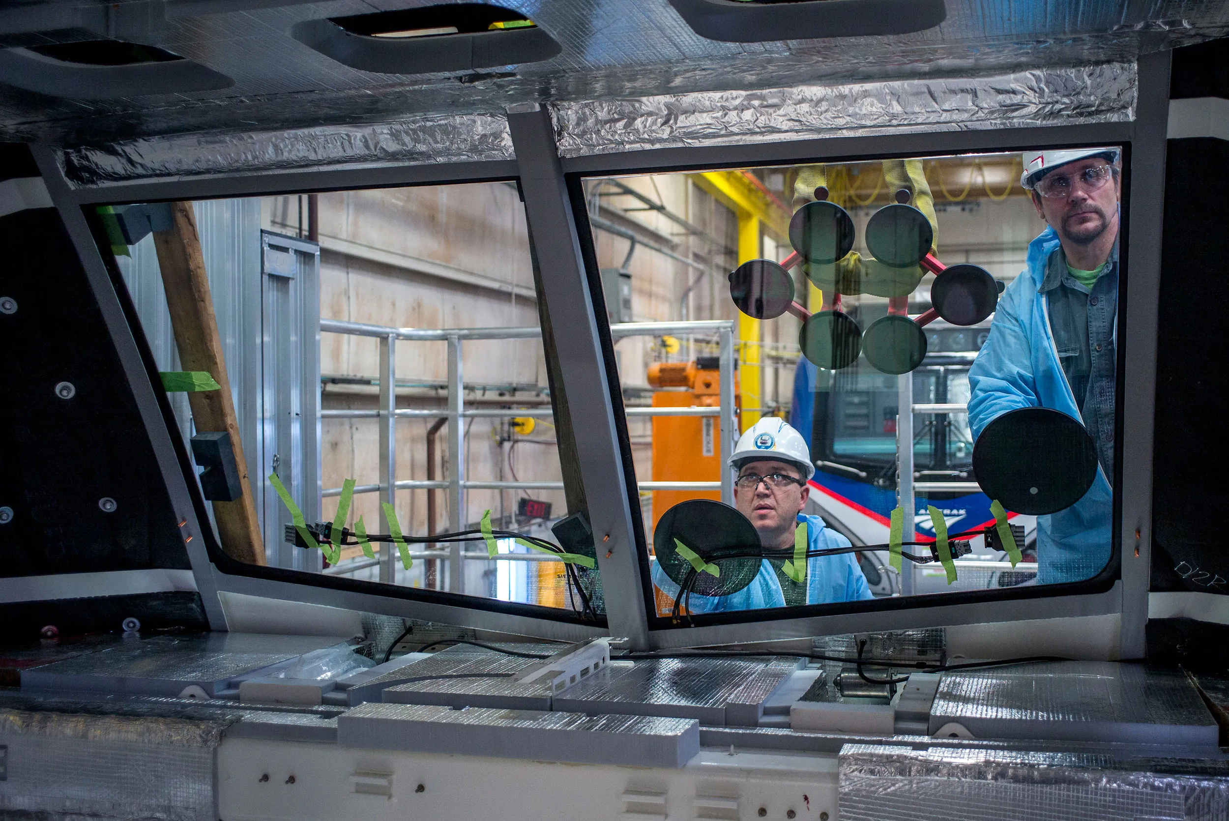 Employees install the windshield of an Amtrak locomotive at a manufacturing facility in Sacramento, California.
