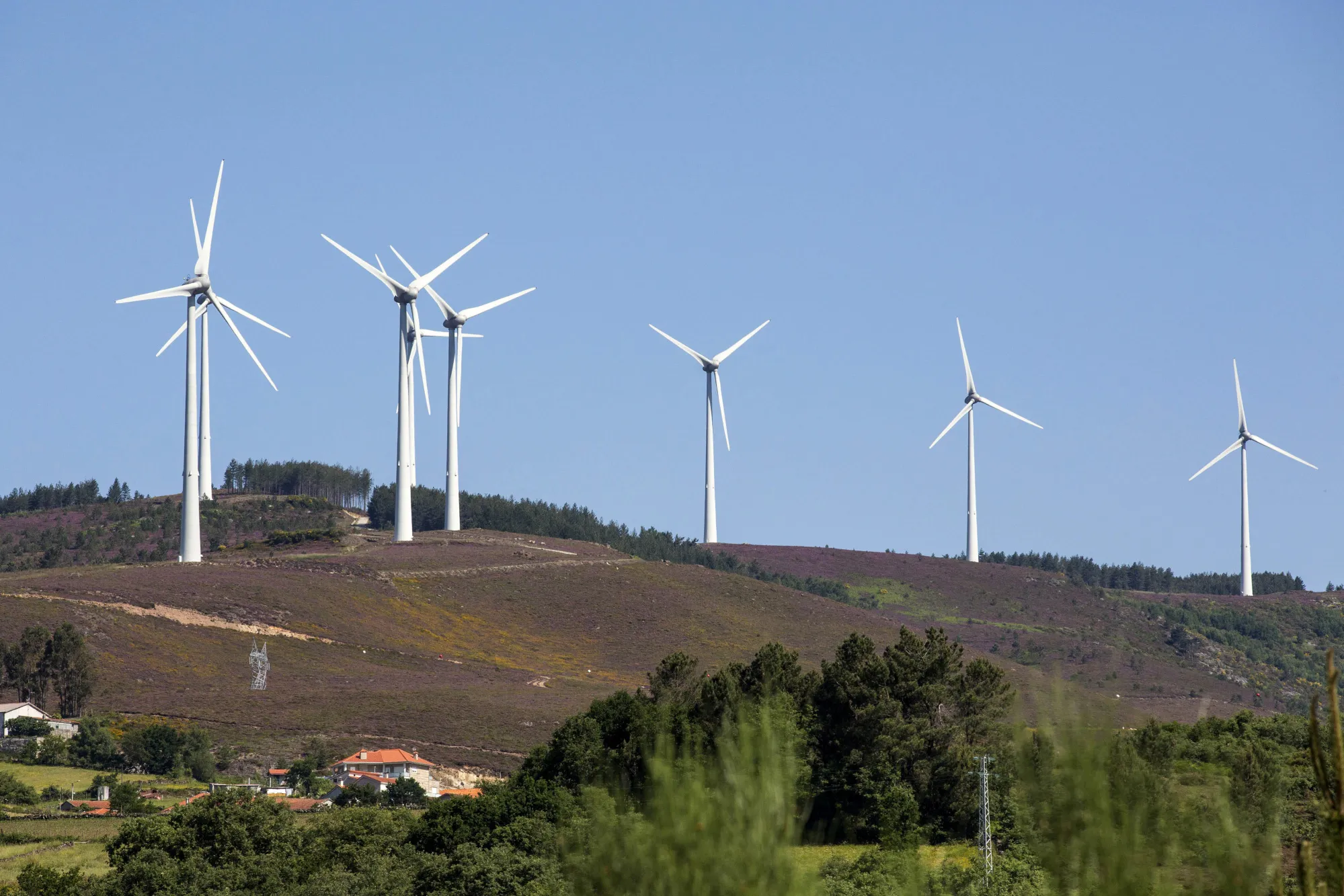 Wind turbines stand on a hill near the hydro electric project by EDP-Energias de Portugal SA's renewables unit, EDP Renovaveis SA in Alto Rabago, Portugal.