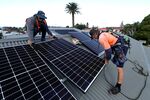 Workers install solar panels onto the rooftop of a residential property in Sydney, earlier in May. 