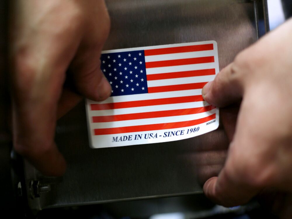 A worker puts a "Made in the USA" sticker on the back of a completed lawnmower at the Dixie Chopper manufacturing facility.