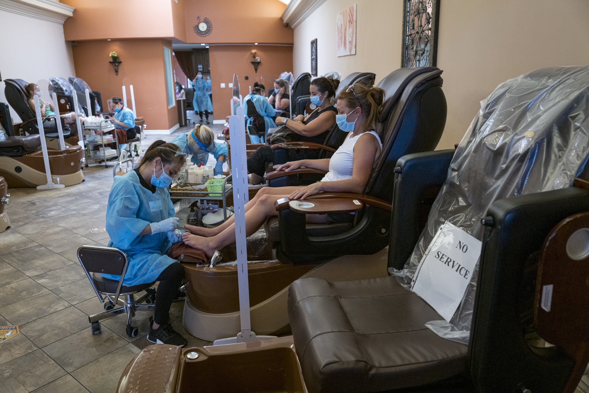 Workers wearing personal protective equipment (PPE) help customers wearing protective masks at a nail salon in Palo Alto, California, on&nbsp;July 14.
