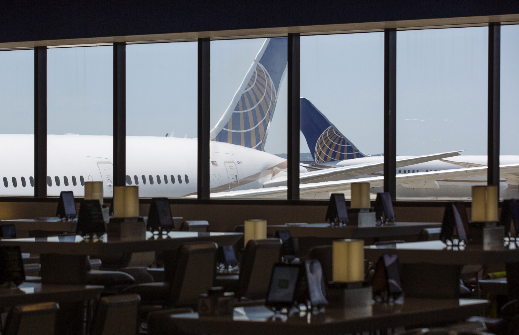 United Airlines Holdings airplanes stand past an empty waiting area at Newark International Airport on June 9.