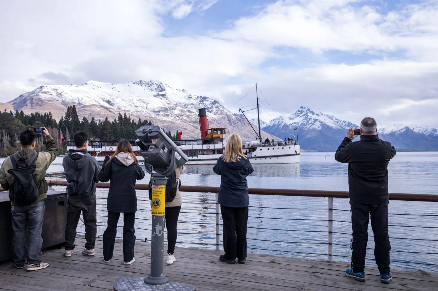 People take photographs from the waterfront in Queenstown, New Zealand.