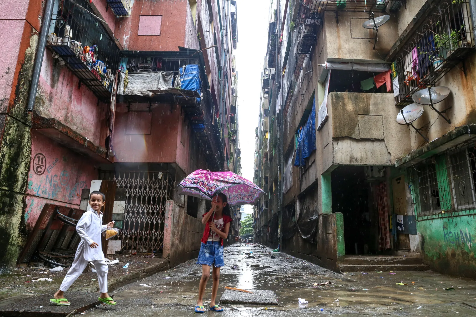 Children play in the rain outside their house in Natwar Parekh,&nbsp;where&nbsp;tuberculosis rates are notably high.