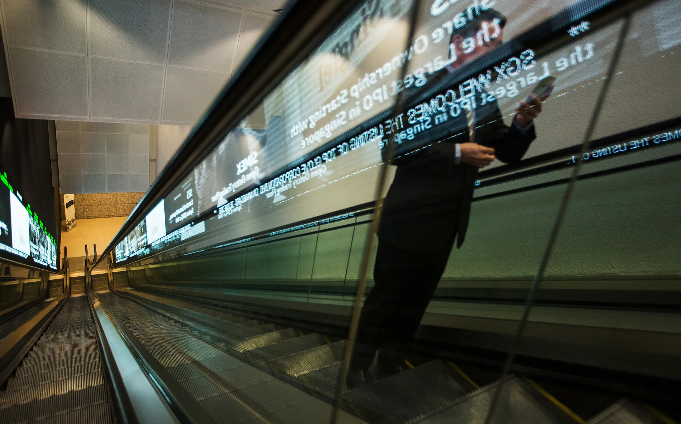 A man rides on an escalator inside the Singapore Stock Exchange building in Singapore, on Tuesday, June 28, 2016.
