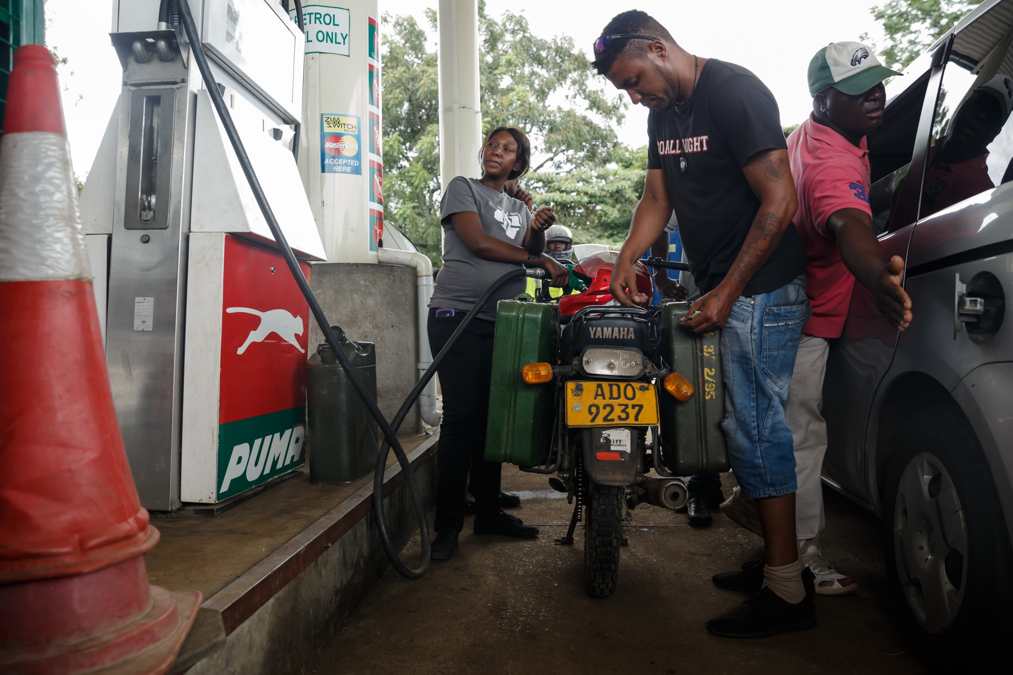 A petrol attendant serves a motorcyclist with two jerry cans attached to his motorbike in Harare on Jan. 11.