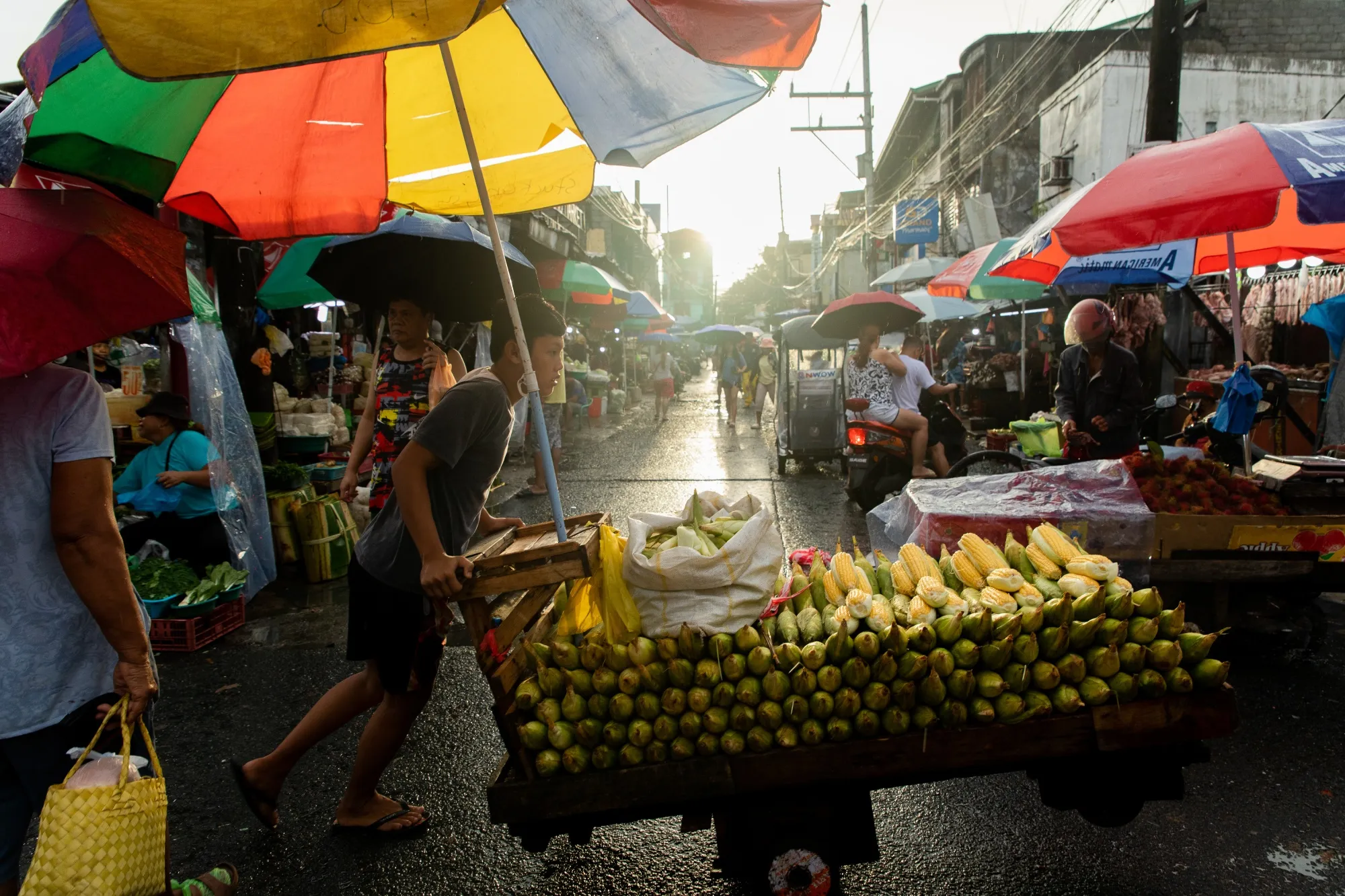 A corn vendor pushes a cart through a street market in Taguig City, the Philippines.