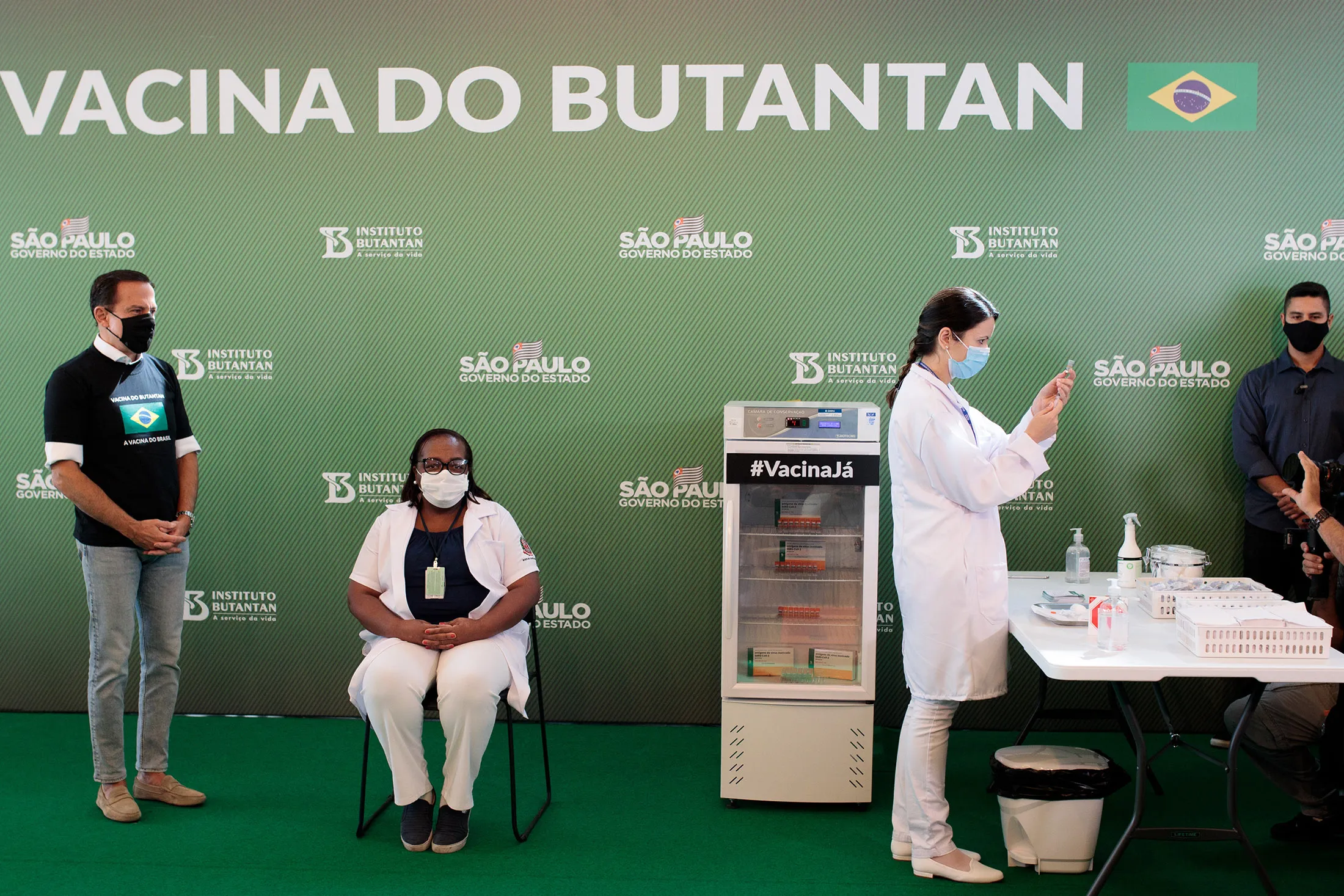 Joao Doria, left, watches as a healthcare worker receives a dose of the Sinovac Biotech vaccine in Sao Paulo on Jan. 17.
