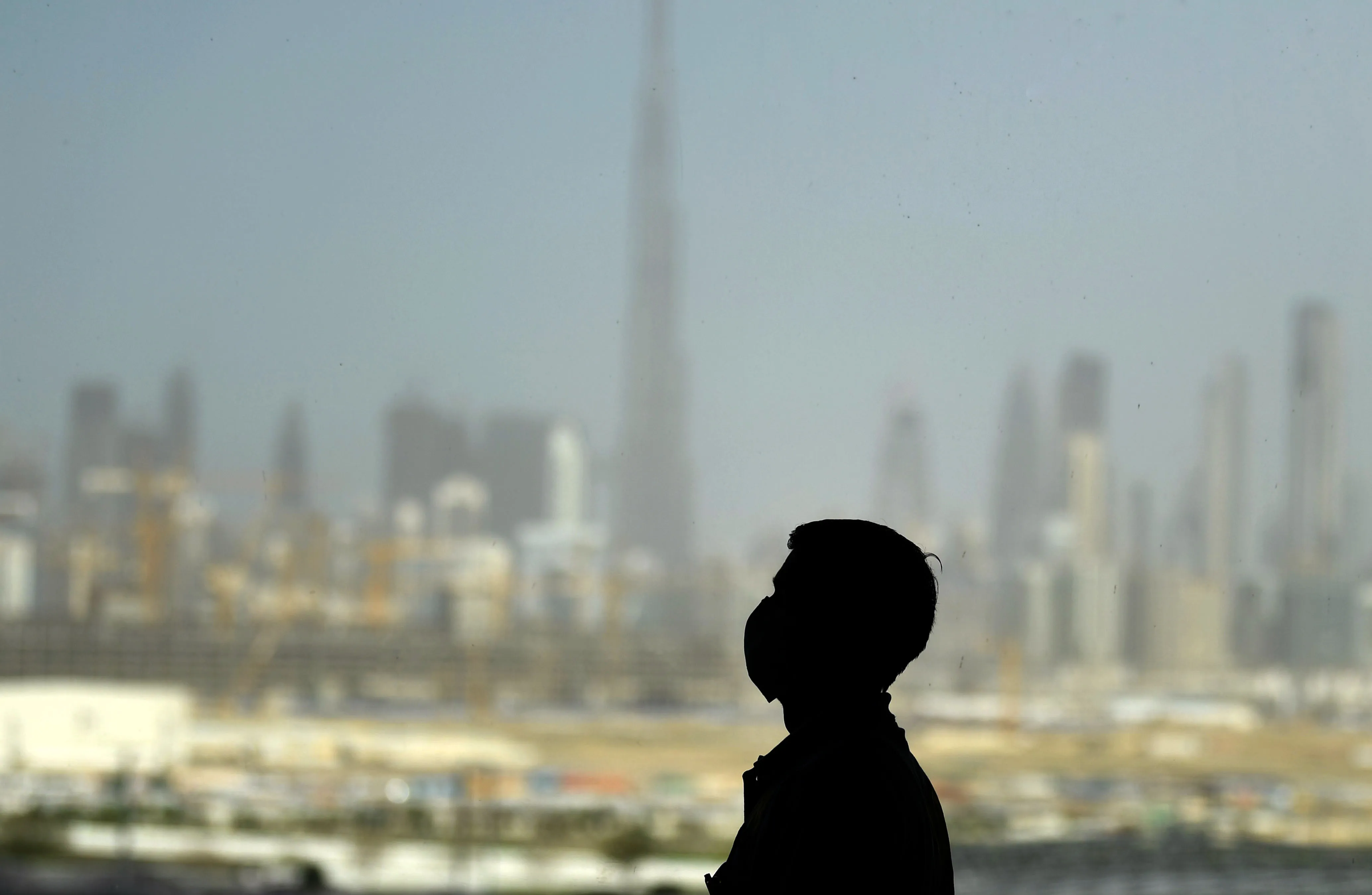 A man wears&nbsp;a protective mask against the city skyline in Dubai, on March 23.