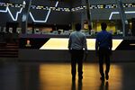 Traders walk as tickers display stock prices inside the Indonesia Stock Exchange (IDX) in Jakarta, Indonesia.