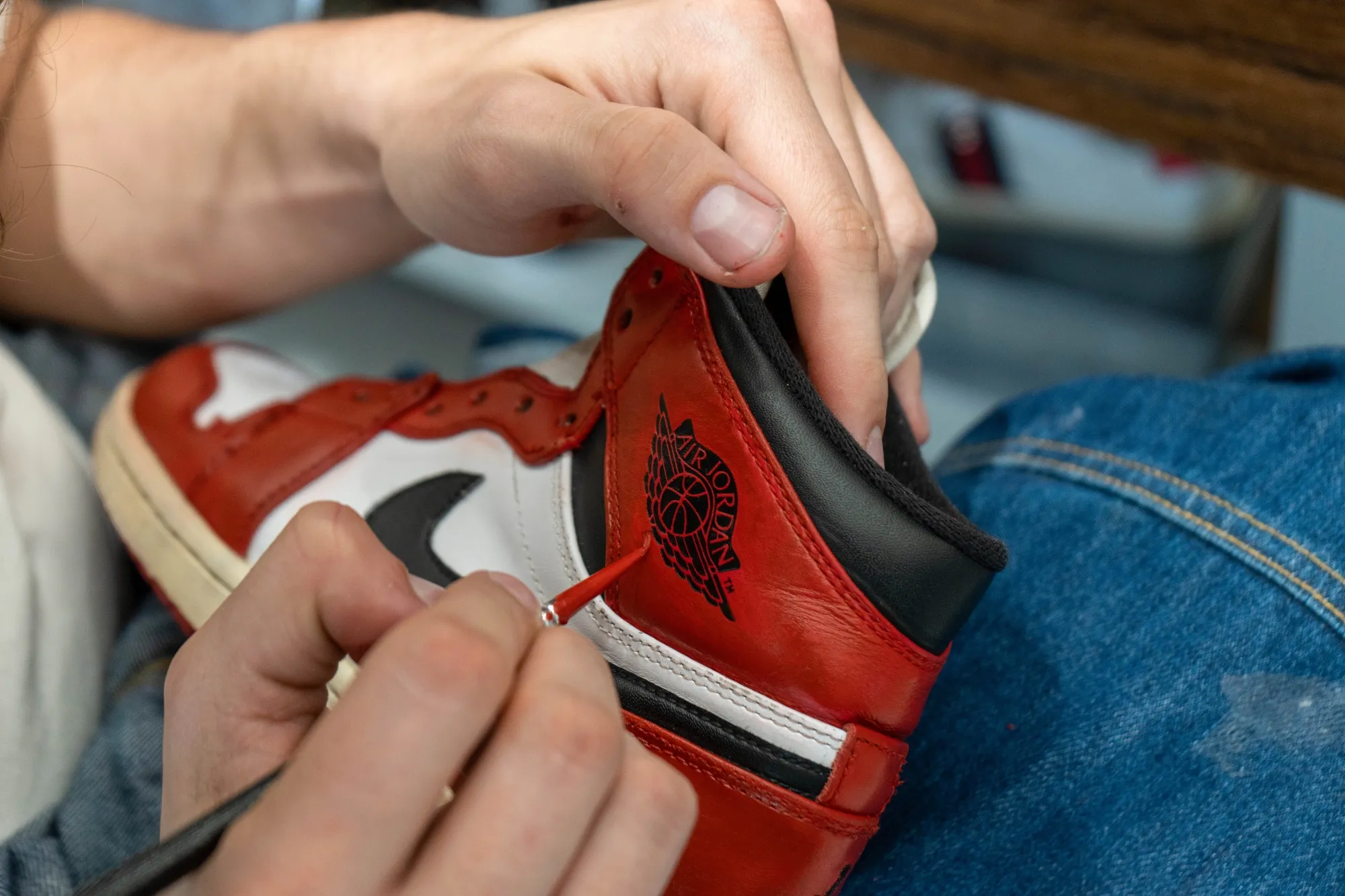 A cobbler paints a Nike Air Jordan sneaker on the customizing desk at a Golden Goose store in Milan, Italy.