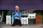 A pedestrian passes fruit and vegetables behind a partially-open shutter in London, U.K., on Friday, June 12, 2020. 