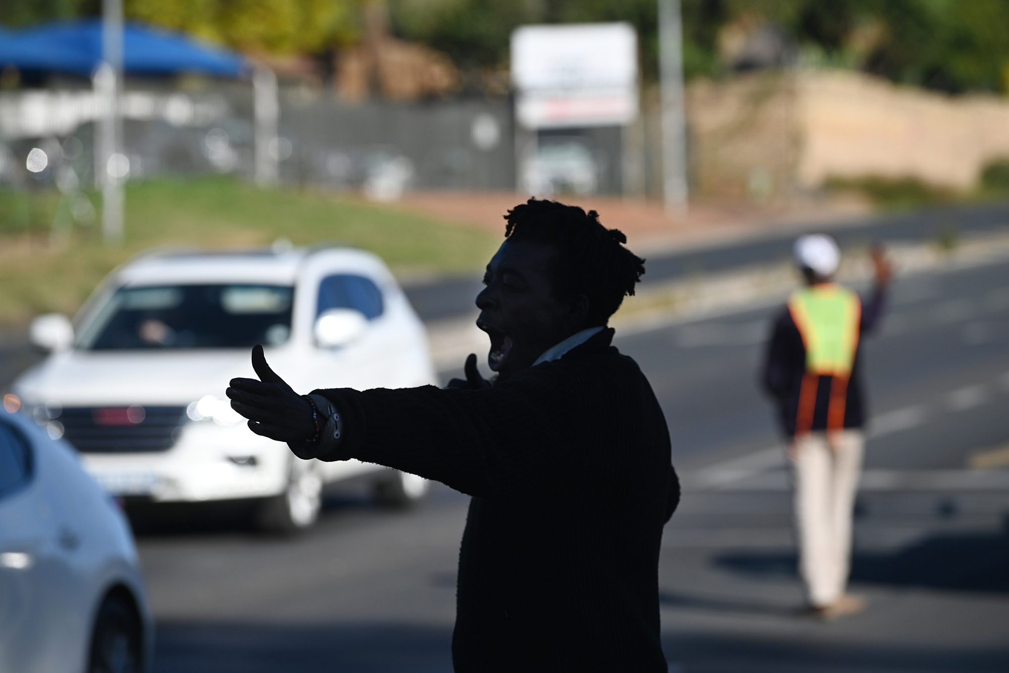 A self-appointed traffic controller directs traffic, to make money from driver tips, while traffic lights are down during a power shutdown, known locally as loadshedding, in Johannesburg, South Africa, on Tuesday, May 23, 2023. Africa's richest city was built on gold, but it's now defined by chaos, crime and corruption more than ever and encapsulates the wider collapse of basic services across South Africa. Photographer: Leon Sadiki/Bloomberg