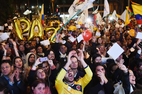 Colombians celebrate as they watch the signing of peace talks on a giant screen in Bogota on Aug. 24.