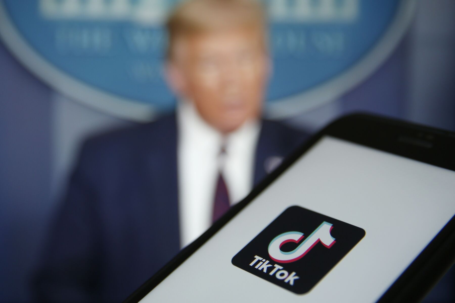 The TikTok logo is displayed in the app store in this arranged photograph in view of a video feed of U.S. President Donald Trump in London, U.K., on Monday, Aug. 3, 2020. 