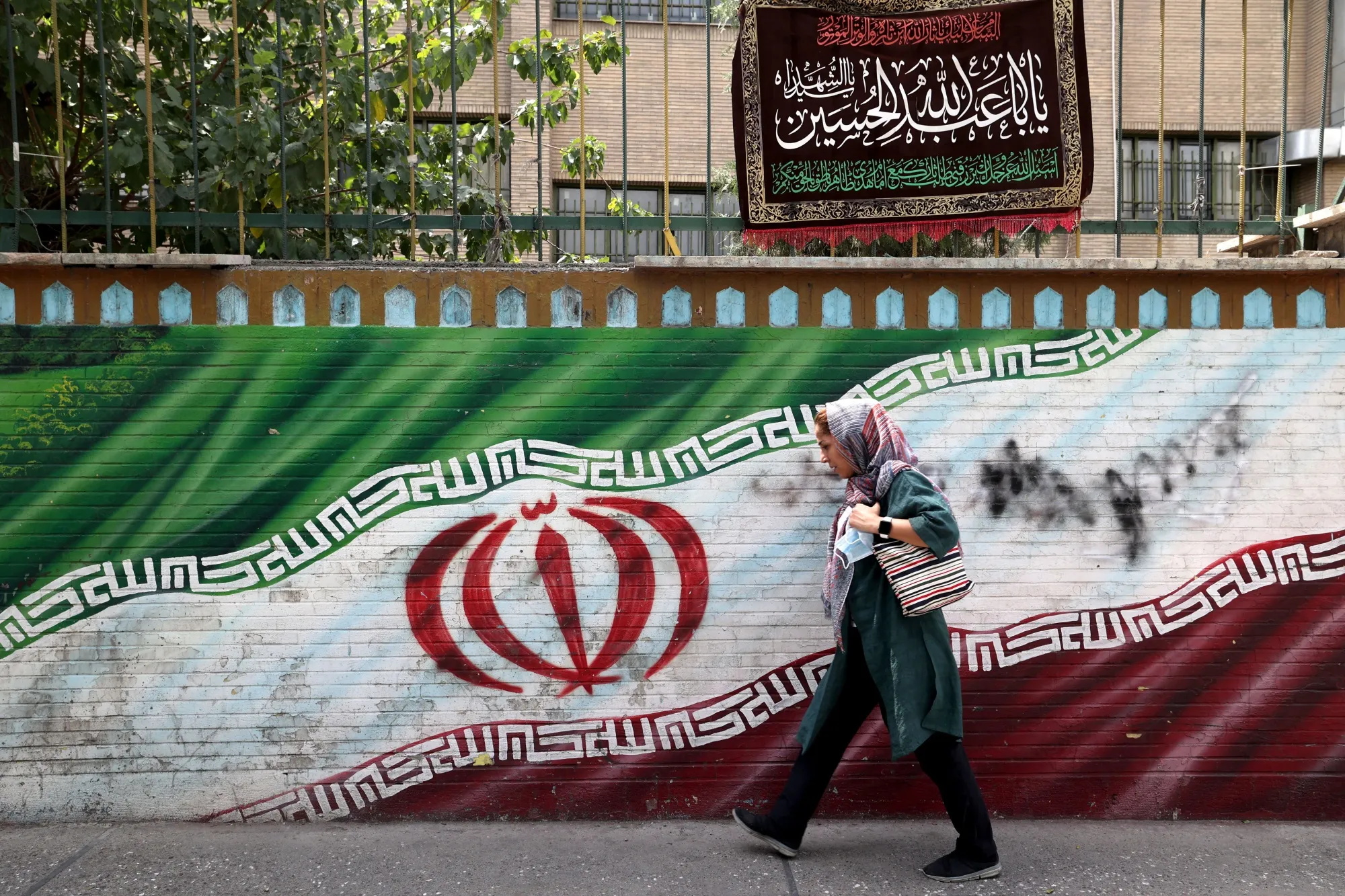 An Iranian woman walks past a mural in the capital Tehran. Photographer: Atta Kenare/AFP/Getty Images
