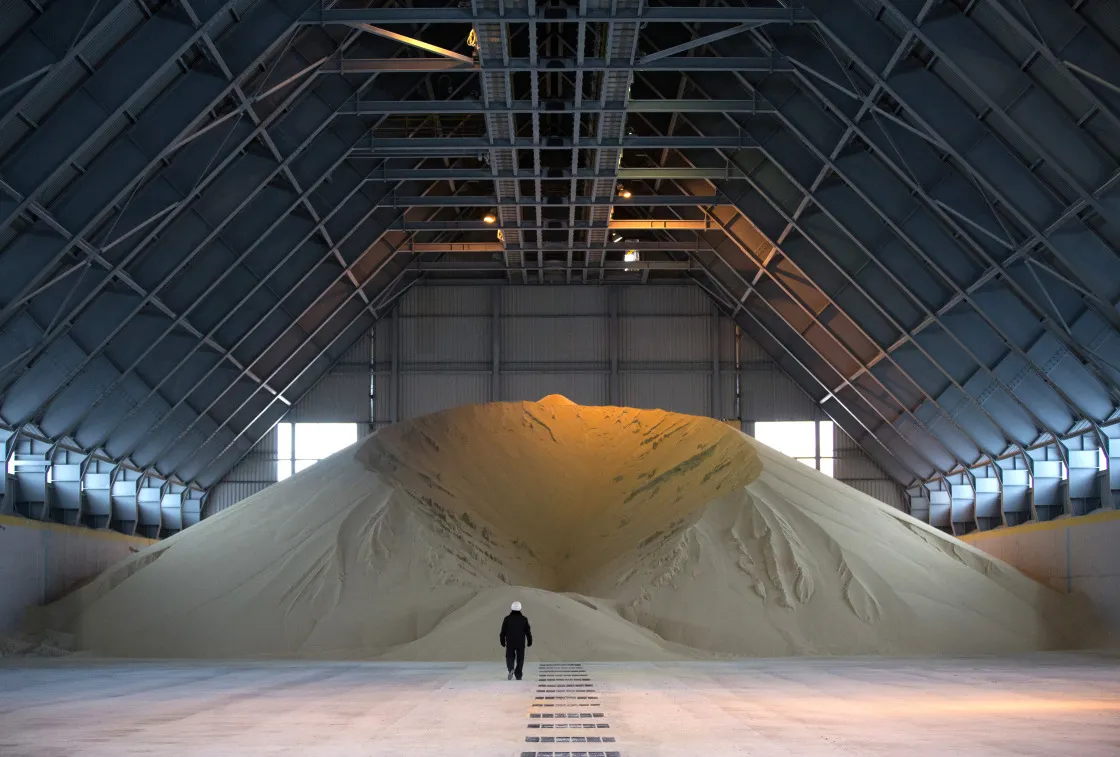 A worker walks towards a large pile of phosphate fertilizer inside a building at a fertilizer&nbsp;plant in Cherepovets, Russia.