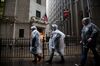 Pedestrians wear ponchos while walking past the New York Stock Exchange (NYSE) in the rain in New York, U.S., on Wednesday, Feb. 24, 2016.