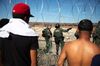 U.S. Customs and Border Protection officers are seen across barbed wire as Central American migrants gather along the US and Mexico border in Tijuana, Mexico, on Nov. 25, 2018.