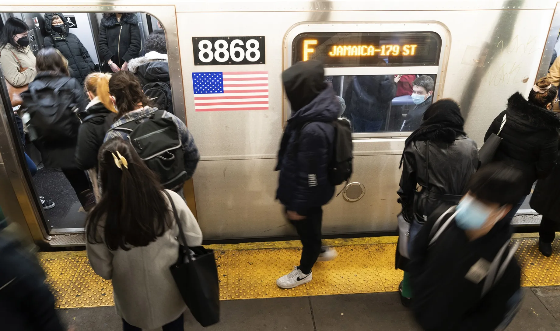 Commuters enter a subway car at a station in New York.