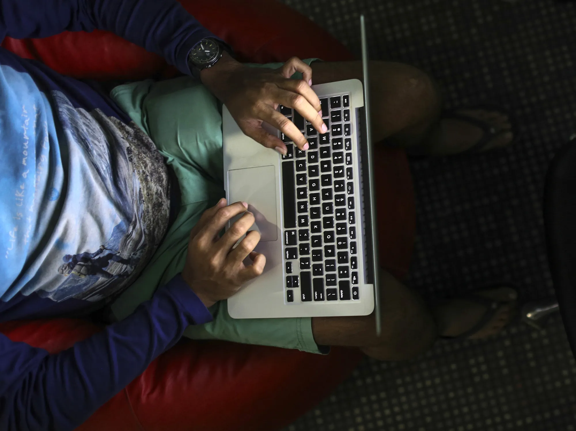 A person is illuminated by the screen of an Apple Inc. laptop computer.