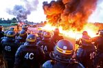 Riot police stand guard behind a fire as refinery workers hold a blockade of the oil depot of Douchy-Les-Mines to protest against the government's proposed labour reforms, on May 25.
