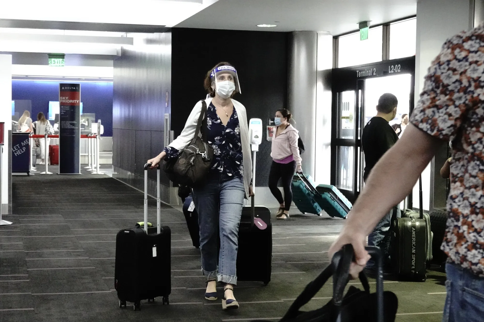 A traveler wearing a protective mask and face shield walks into Terminal 2 at Los Angeles International Airport.