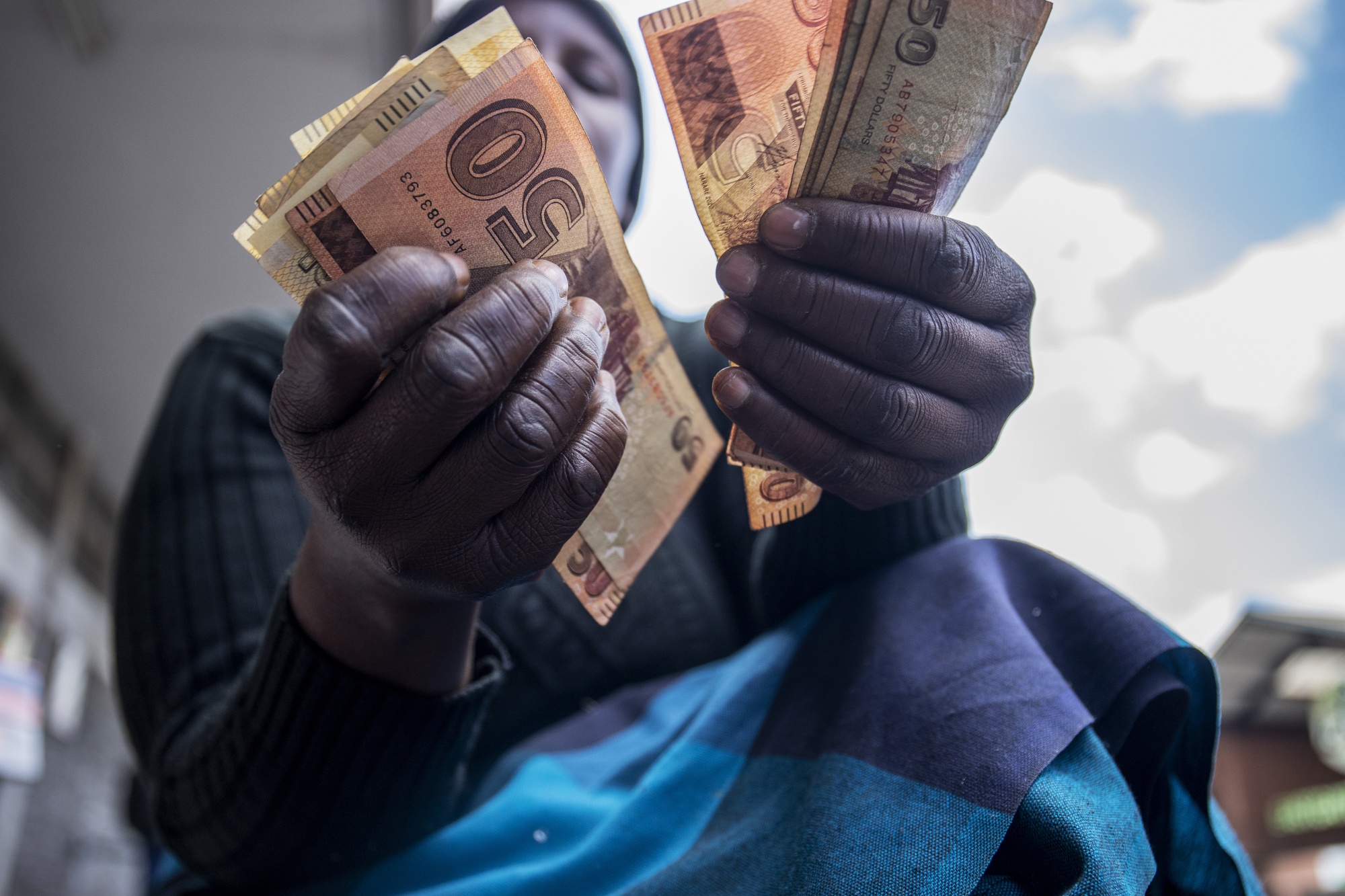 A street vendor counts out Zimbabwean 50 dollar banknotes in Harare.