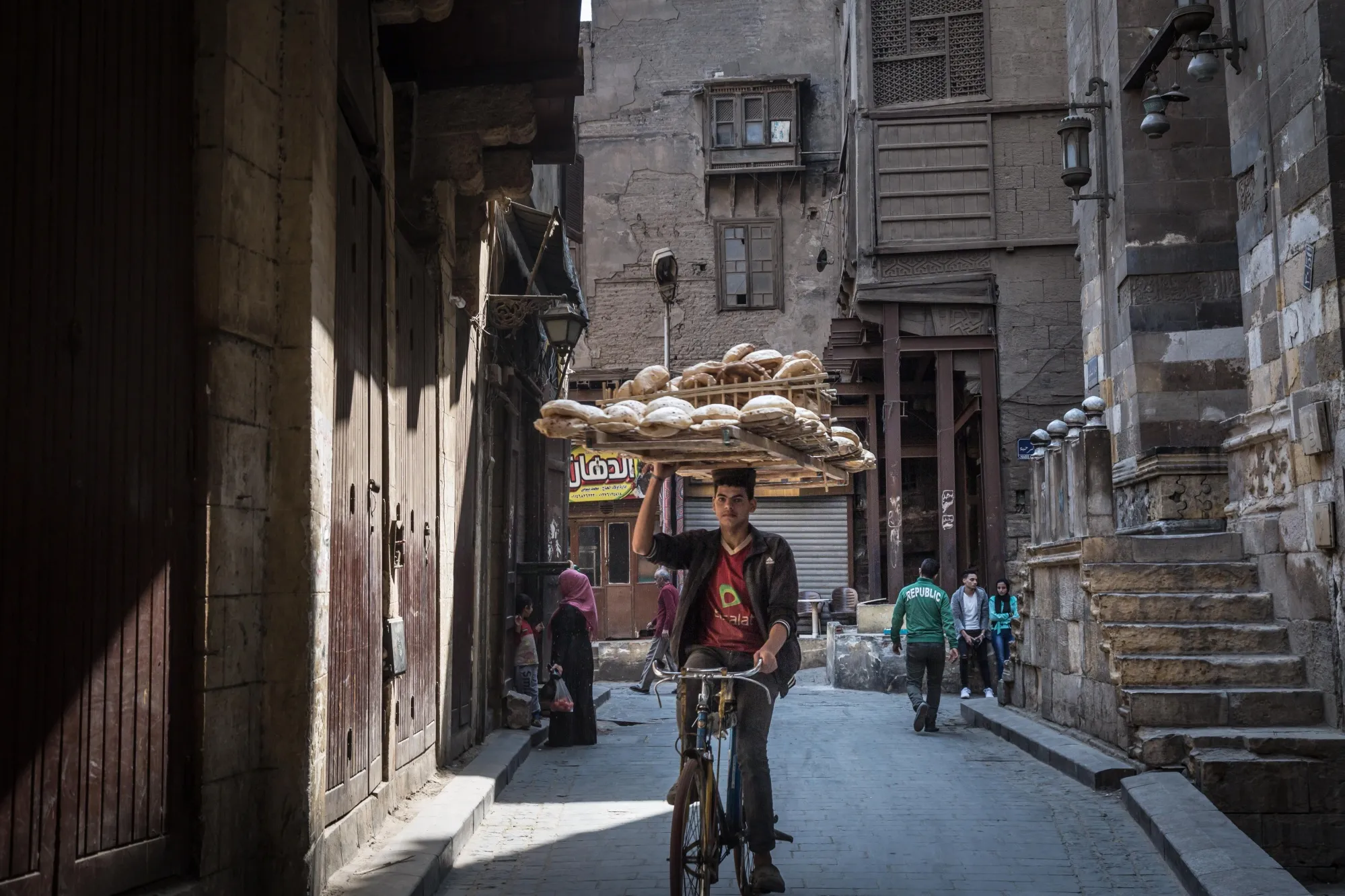 A cyclist balances a bread board on his head as he rides in Cairo.