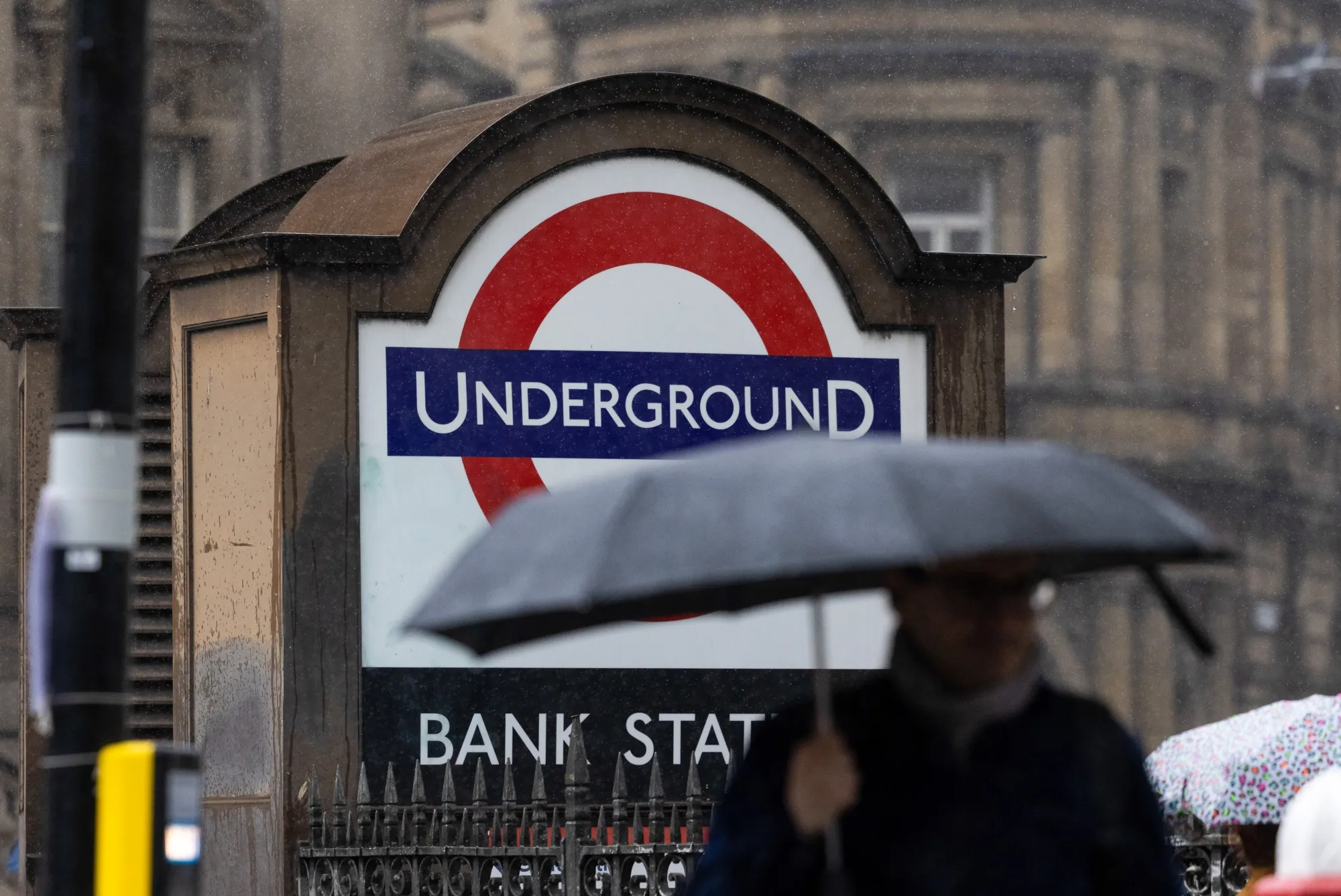 Commuters pass an entrance to the underground station next to the Bank of England (BOE) in the City of London, UK.