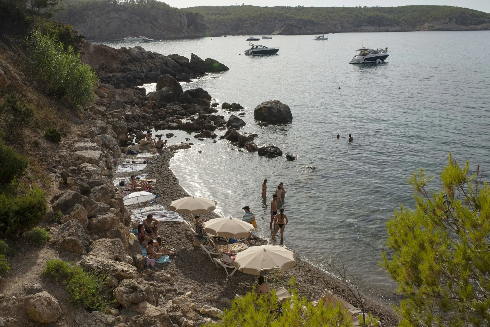 Yachts on the sea and tourists on the sand crowd Ibiza's tiny S'Illot des Renclí cove in Spain on&nbsp;July 23, 2025.